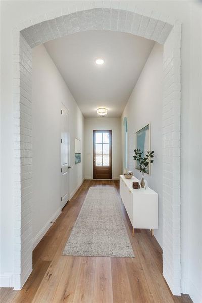 Foyer entrance with light wood-style floors and arched walkways