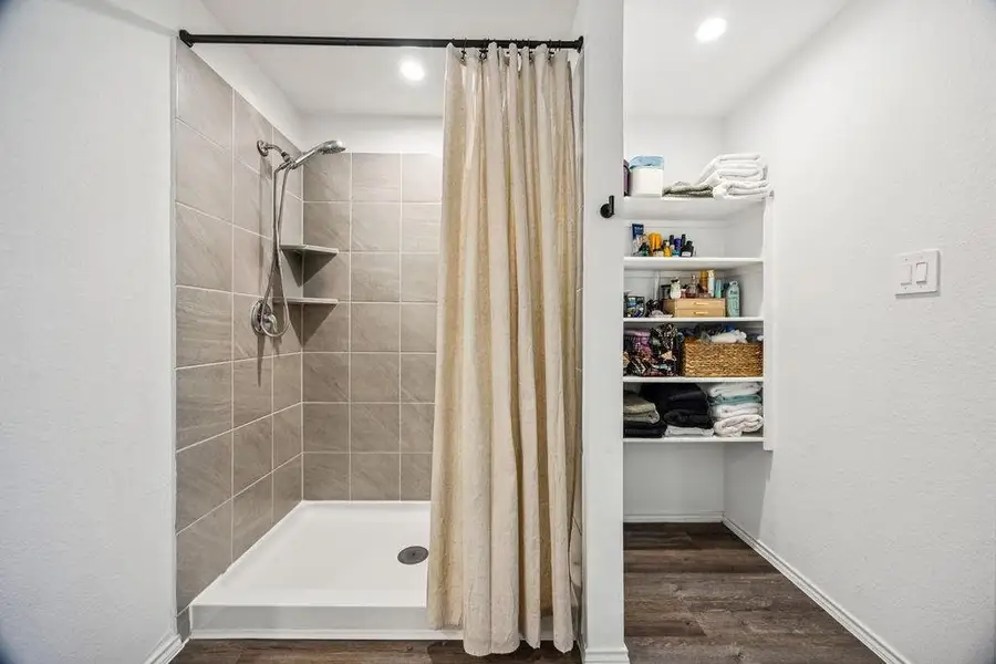 Spacious primary bath featuring a sleek walk-in shower and ample shelving for organized storage. Spacious primary bath featuring a sleek walk-in shower and ample shelving for organized storage.