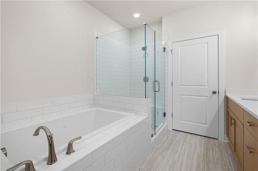 Bathroom featuring vanity, a bath, a stall shower, and recessed lighting