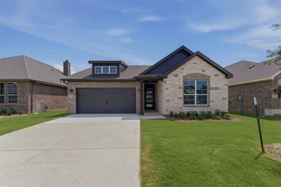 Modern single-story residence featuring a combination brick and stone exterior, a dark gray garage door, and a dormer with multiple windows