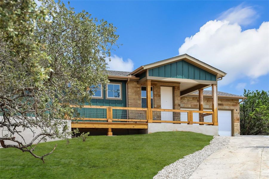 View of front facade featuring stone siding, a front lawn, board and batten siding, and covered porch