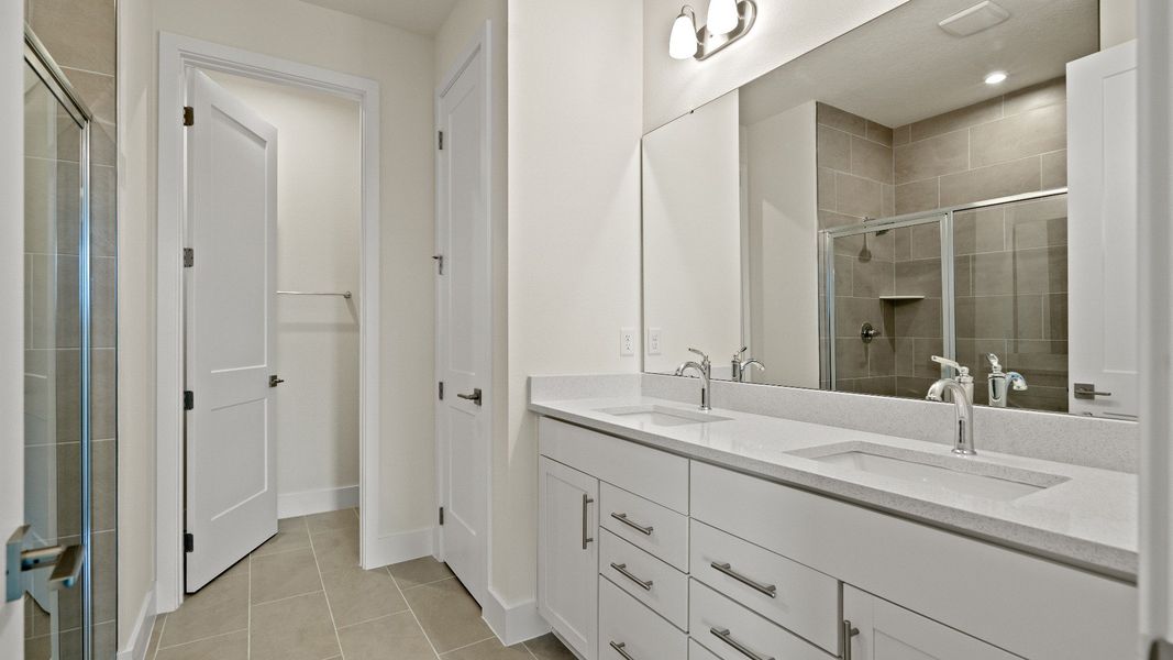 Primary En Suite Bath with Dual Sinks and Walk-In Shower & water closet in the Longleaf by DRB Homes New Home in Saint Cloud