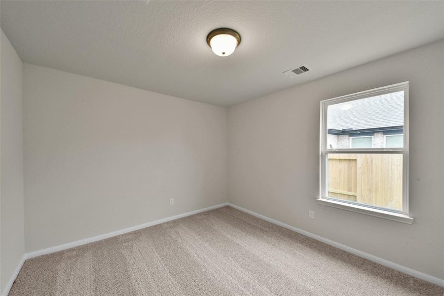 Light-filled third bedroom featuring plush carpeting and a serene, restful atmosphere.