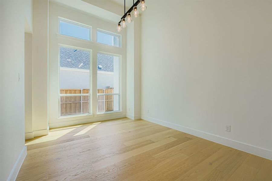 Unfurnished dining area featuring light wood-style flooring and a high ceiling Unfurnished dining area featuring light wood-style flooring and a high ceiling