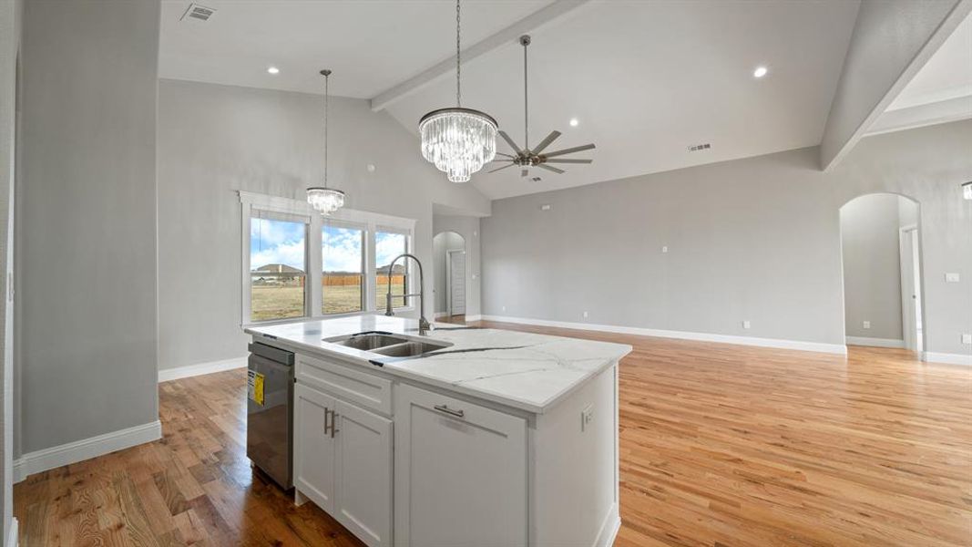 Kitchen with arched walkways, stainless steel dishwasher, a sink, and beam ceiling