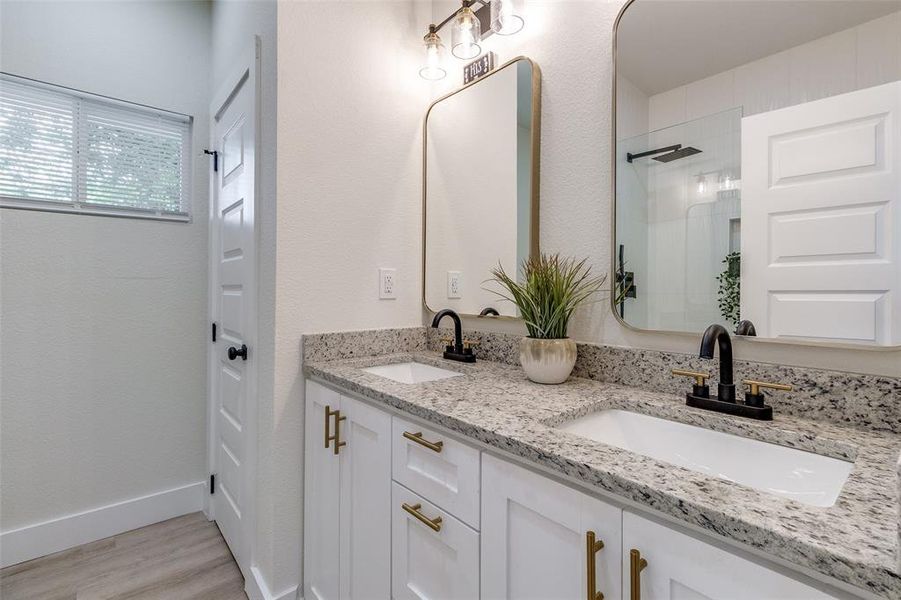 Bathroom with double vanity and hardwood / wood-style flooring