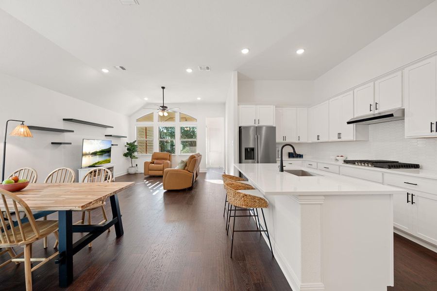 An open concept floorplan seamlessly blends a modern kitchen with a living area, featuring high ceilings and dark hard floors. An open concept floorplan seamlessly blends a modern kitchen with a living area, featuring high ceilings and dark hard floors.
