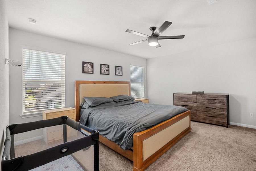 Relax in this tranquil bedroom, featuring soft carpet, a contemporary ceiling fan, and abundant natural light.