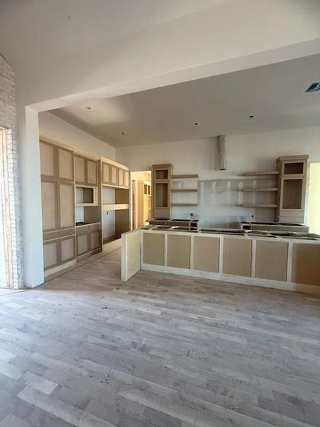 Open floor plan with the kitchen boasting glass front custom cabinets, floating shelves and designer stainless steel appliances. The back wall of the kitchen will be tiled from floor to ceiling. Updates coming soon.