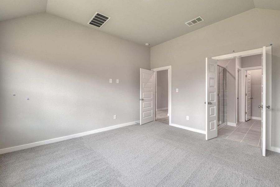Comfortable carpeting and a vaulted ceiling elevate the ambiance of this spacious primary bedroom. Comfortable carpeting and a vaulted ceiling elevate the ambiance of this spacious primary bedroom.