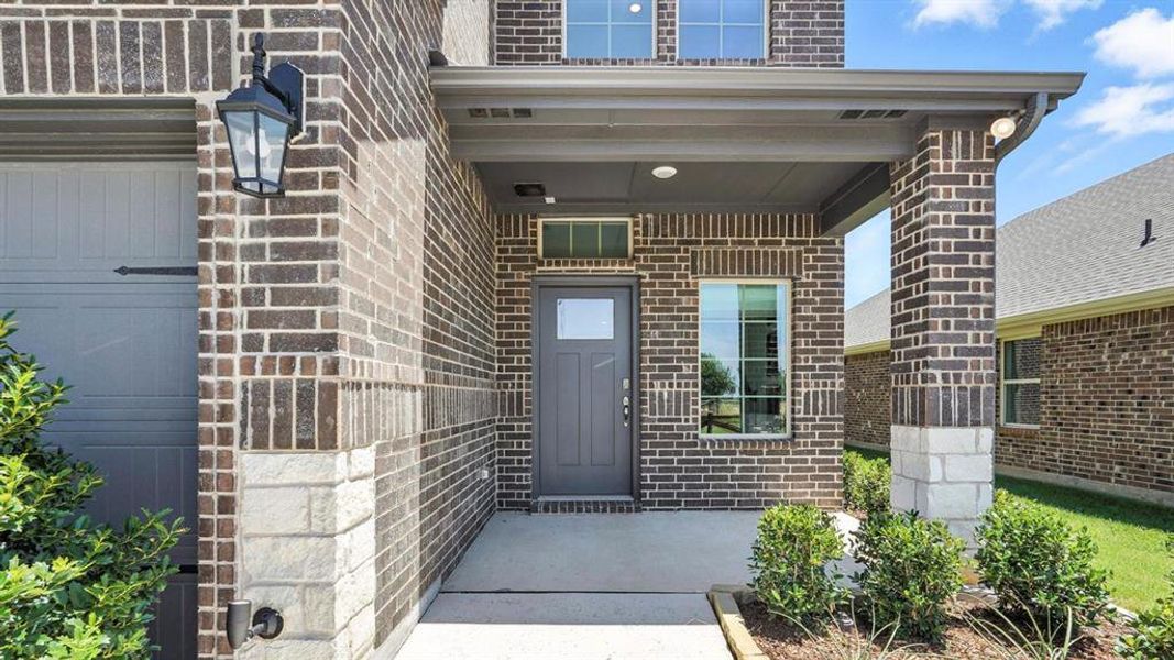 Entrance to property with covered porch and brick siding