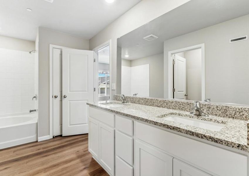 The master bathroom has a large tub/shower and a dual sink vanity.