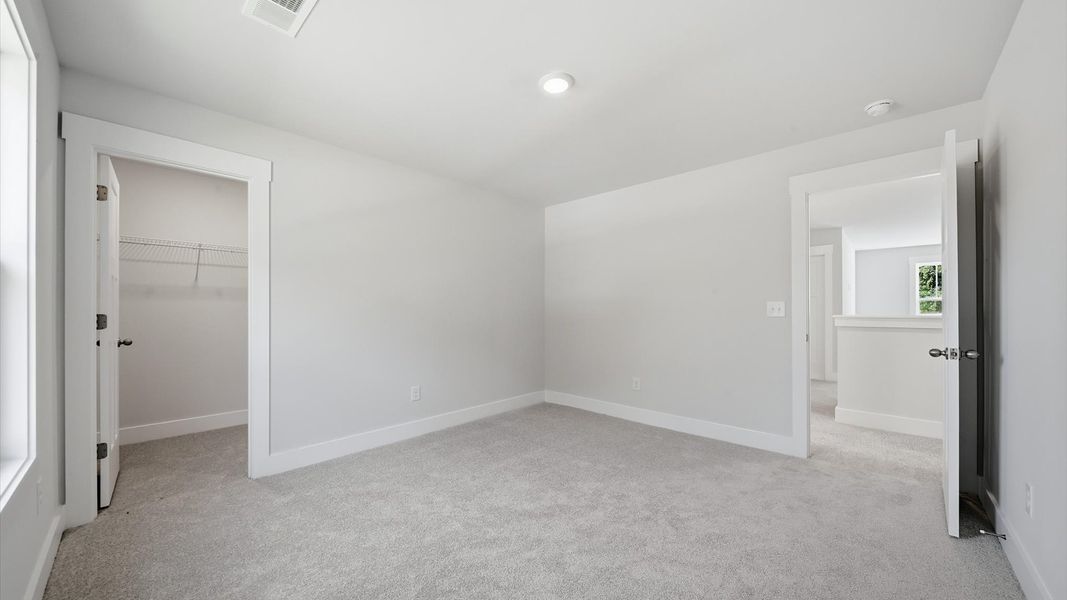 Notable secondary bedroom offering cozy carpeted flooring and a stylish walk-in closet