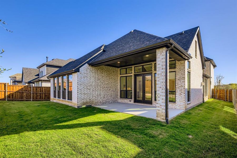 Rear view of house featuring a fenced backyard, a patio, brick siding, a shingled roof, and french doors