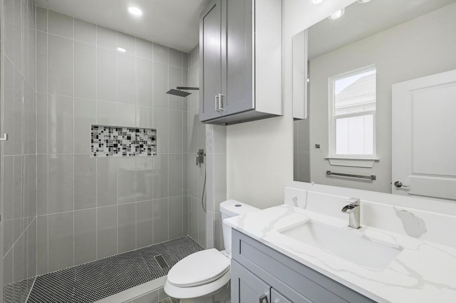 Bathroom with vanity, a tile shower, and recessed lighting