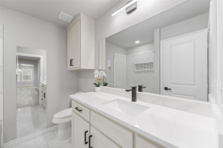 Bathroom vanity featuring a single basin, white countertop, and matte black faucet Bathroom vanity featuring a single basin, white countertop, and matte black faucet
