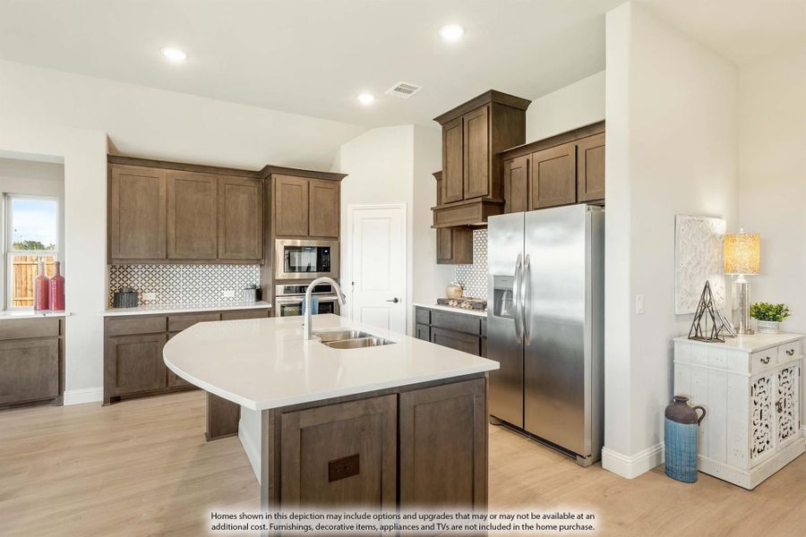 Kitchen with dark wood cabinets, center island with sink, and stainless steel refrigerator on light hardwood floors Kitchen with dark wood cabinets, center island with sink, and stainless steel refrigerator on light hardwood floors