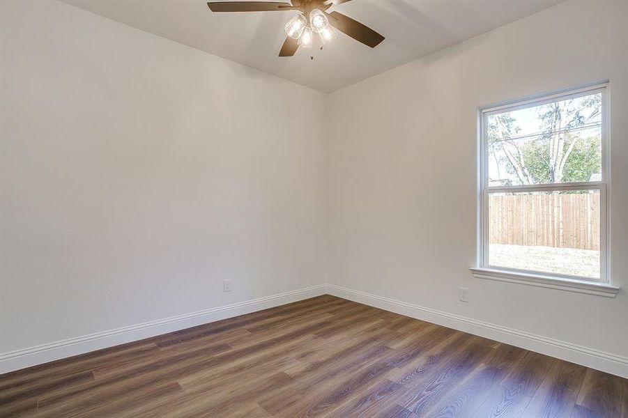 Spare room featuring baseboards and dark wood-type flooring
