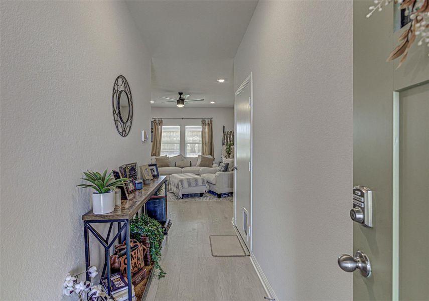 Corridor featuring a textured wall, light wood-style floors, and recessed lighting