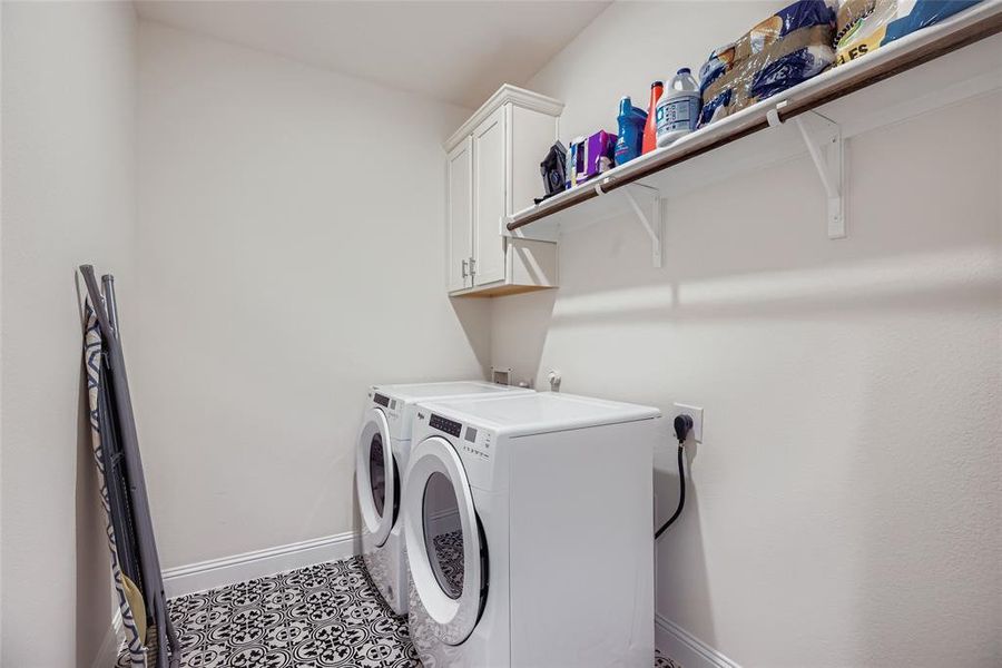 Laundry area featuring cabinet space, washer and clothes dryer, and tile patterned floors