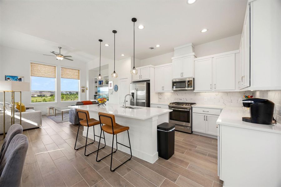Modern white cabinetry with silver pulls and under cabinet lighting add a luxurious feel to the kitchen area.