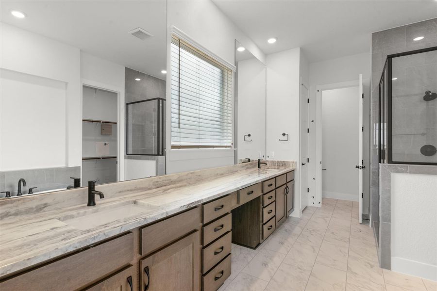 Full bathroom featuring double vanity, a spacious closet, a stall shower, light marble finish floors, and recessed lighting