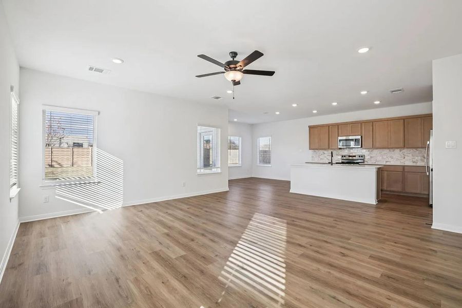 An open concept living area transitions effortlessly into a contemporary kitchen, showcasing warm wood cabinetry and sleek appliances. An open concept living area transitions effortlessly into a contemporary kitchen, showcasing warm wood cabinetry and sleek appliances.