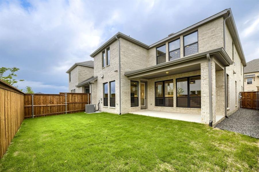 Expansive fenced backyard featuring a covered patio, manicured lawn, and multi-pane windows Expansive fenced backyard featuring a covered patio, manicured lawn, and multi-pane windows