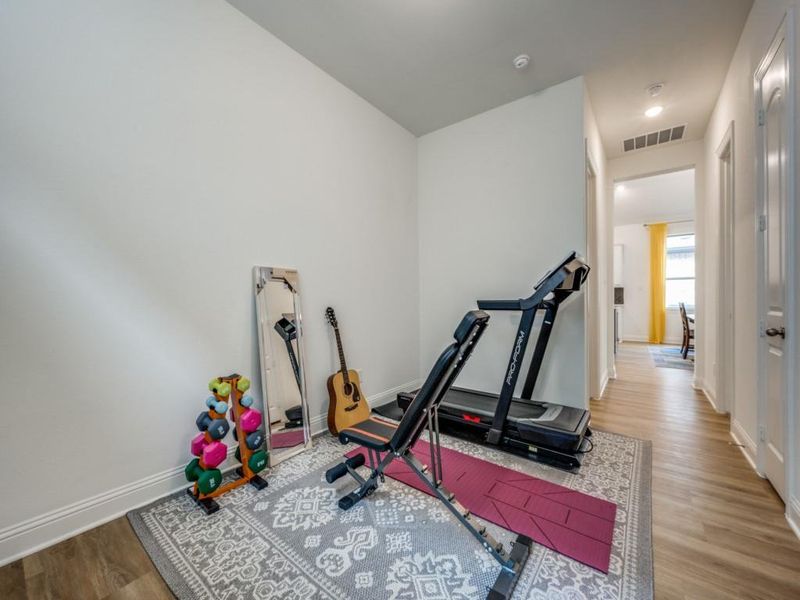 Workout room with wood finished floors, baseboards, and visible vents