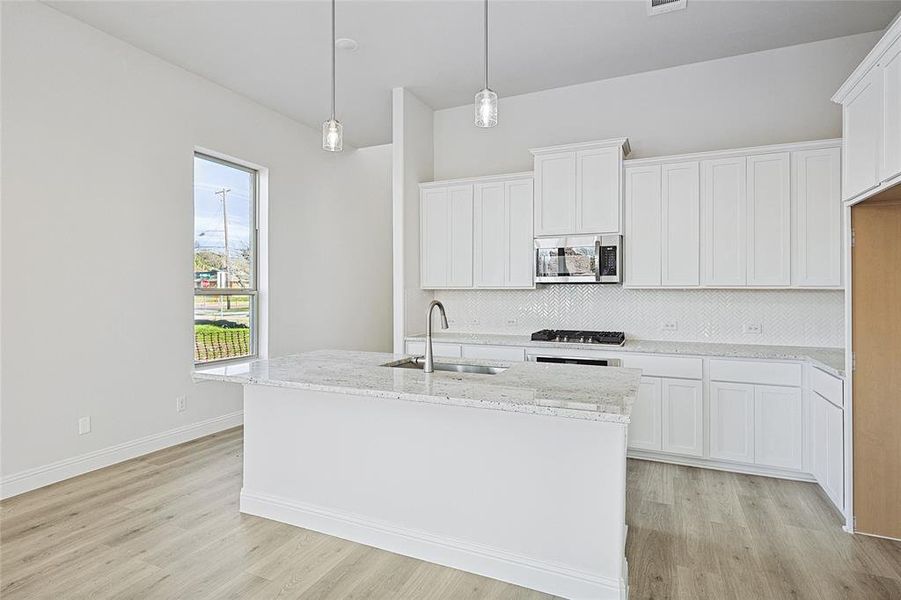 Kitchen featuring a center island with sink, sink, white cabinetry, and stainless steel appliances