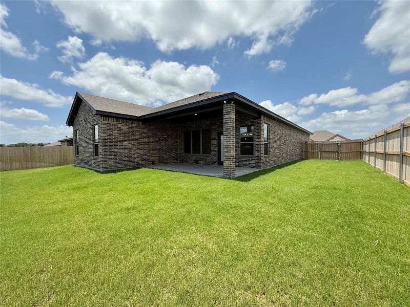 Rear view of house featuring brick siding, a patio, and a fenced backyard