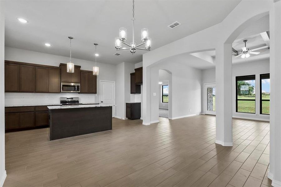 Kitchen featuring range, ceiling fan with notable chandelier, tasteful backsplash, and light wood-type flooring