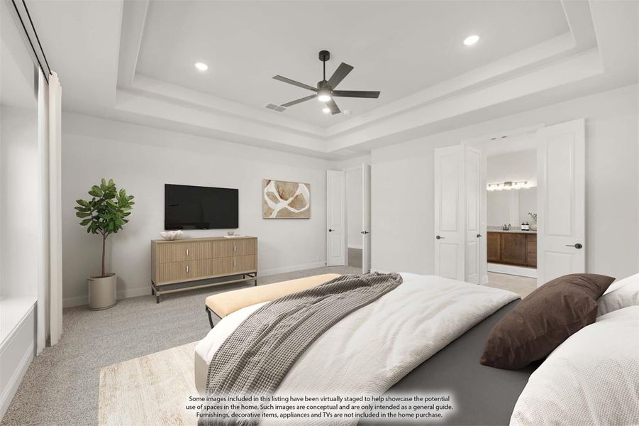 Master bedroom with tray ceiling, ceiling fan, carpet flooring, and ensuite bathroom doorway visible. Master bedroom with tray ceiling, ceiling fan, carpet flooring, and ensuite bathroom doorway visible.