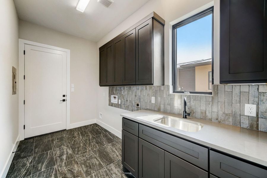 The laundry room, just off the garage, features cabinets, sink, and window that lets in just the right amount of natural light.