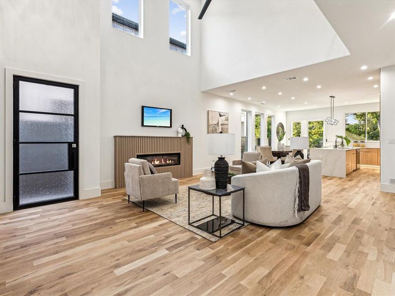 Living room featuring sink, light wood-type flooring, and a high ceiling