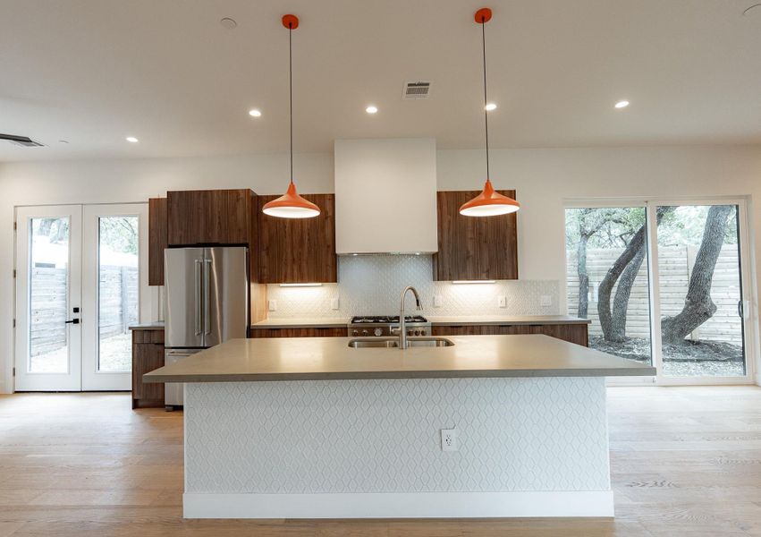 A well-lit kitchen boasts warm wood cabinetry, a spacious island, and seamless outdoor access. A well-lit kitchen boasts warm wood cabinetry, a spacious island, and seamless outdoor access.
