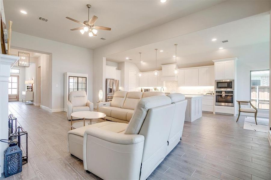 Living area with a ceiling fan, light wood-style floors, plenty of natural light, recessed lighting, and vaulted ceiling Living area with a ceiling fan, light wood-style floors, plenty of natural light, recessed lighting, and vaulted ceiling