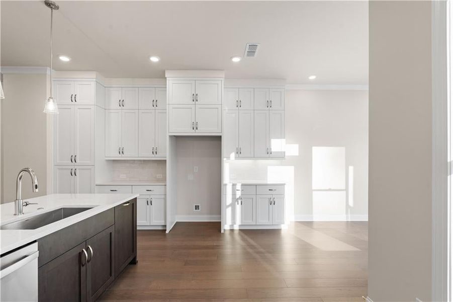 Kitchen with white cabinetry, dark brown cabinetry, decorative light fixtures, stainless steel dishwasher, and dark wood finished floors Kitchen with white cabinetry, dark brown cabinetry, decorative light fixtures, stainless steel dishwasher, and dark wood finished floors