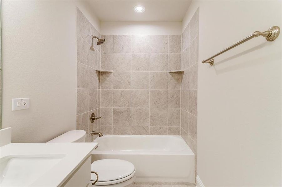 Full bathroom with tiled shower / bath, vanity, and toilet