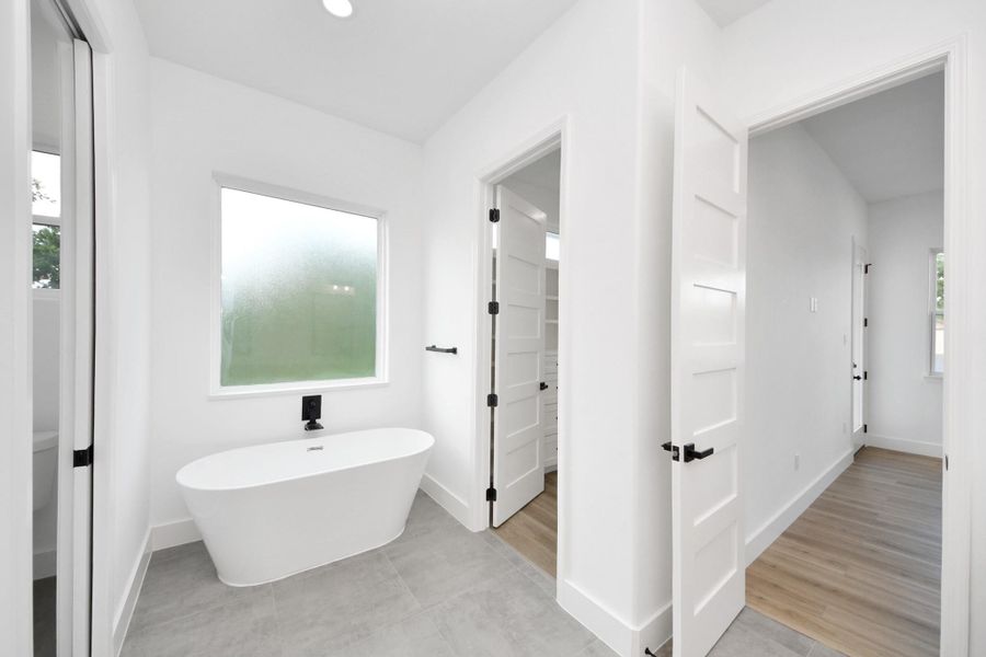 Primary bathroom w/ large soak in tub, frosted window for natural light.