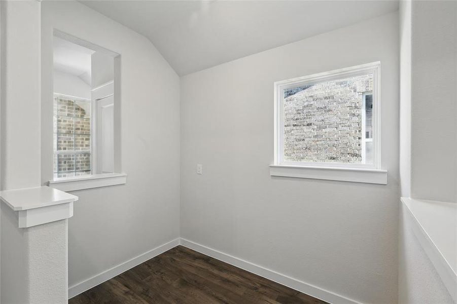 Spare room featuring vaulted ceiling, dark wood-type flooring, and healthy amount of natural light Spare room featuring vaulted ceiling, dark wood-type flooring, and healthy amount of natural light