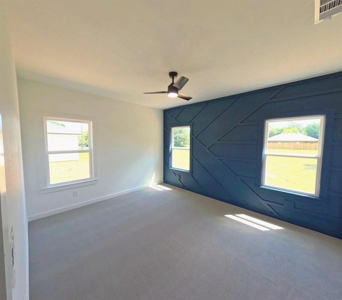 Carpeted spare room with healthy amount of natural light and a ceiling fan Carpeted spare room with healthy amount of natural light and a ceiling fan