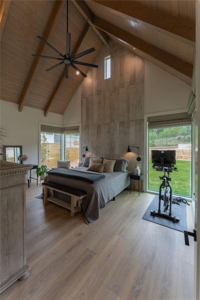 Vaulted wood-finish ceiling with exposed beams, plank accent wall, large windows, and wood-finish flooring Vaulted wood-finish ceiling with exposed beams, plank accent wall, large windows, and wood-finish flooring