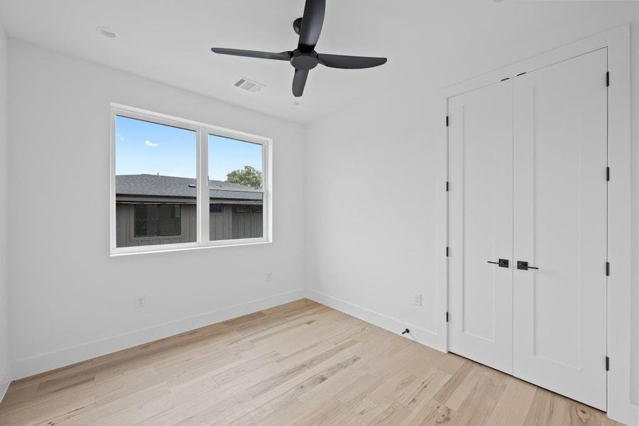 Unfurnished bedroom featuring light wood-style floors, a ceiling fan, and a closet