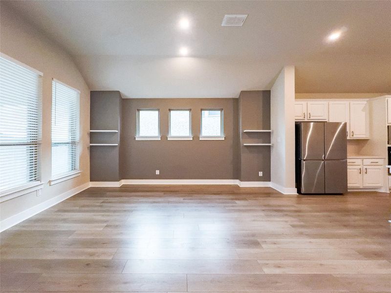 Unfurnished living room featuring light wood-type flooring and lofted ceiling Unfurnished living room featuring light wood-type flooring and lofted ceiling