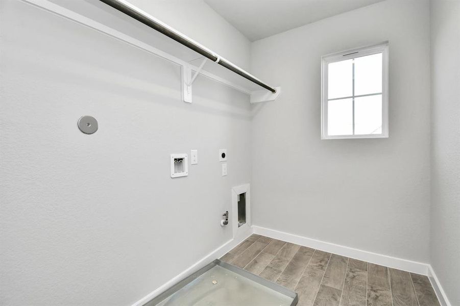 A spacious utility room with ample shelving for organization. It features connections for both gas and electric dryers, making it versatile and functional for all laundry needs.