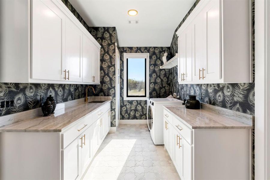 Laundry room featuring cabinet space, independent washer and dryer, and wallpapered walls Laundry room featuring cabinet space, independent washer and dryer, and wallpapered walls