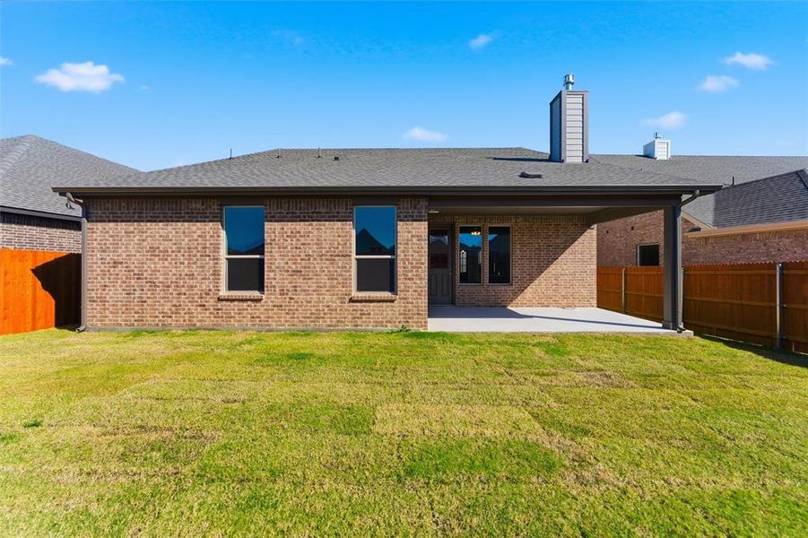 Back of property with a fenced backyard, a shingled roof, a chimney, a patio area, and brick siding