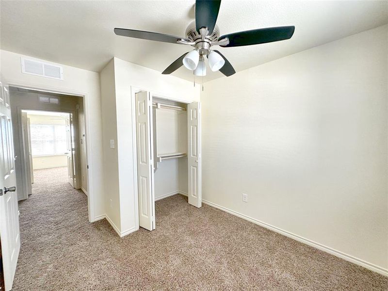 Unfurnished bedroom featuring light colored carpet, a closet, and ceiling fan