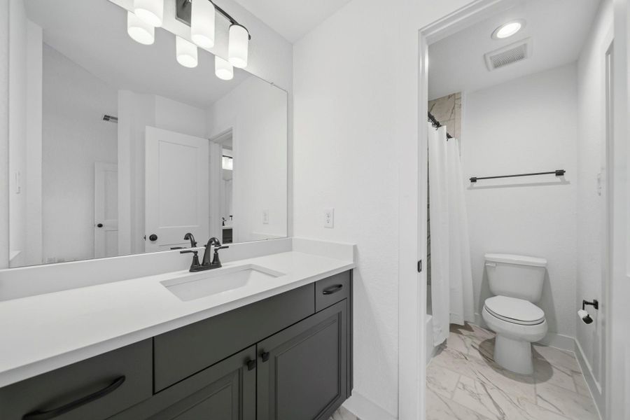A jack and jill bathroom is the perfect set up for sharing! This private vanity area features an oversized vanity with quartz countertops, a large mirror, and plenty of storage.